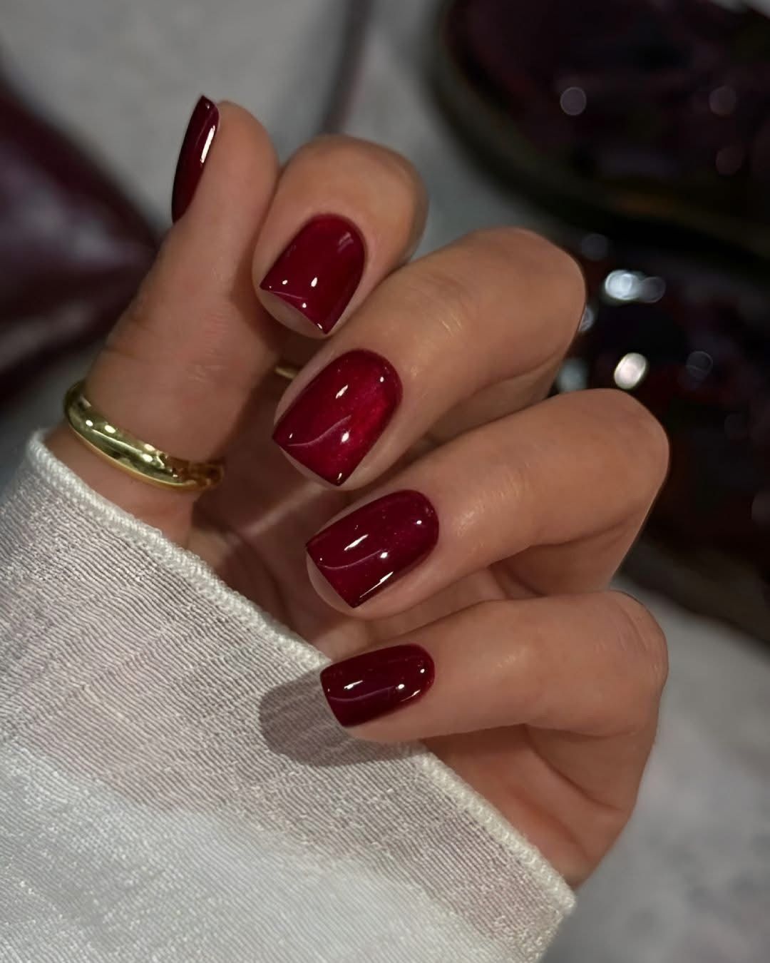 Ongles courts carrés avec un vernis rouge cerise brillant et un subtil détail marbré blanc sur deux doigts.
