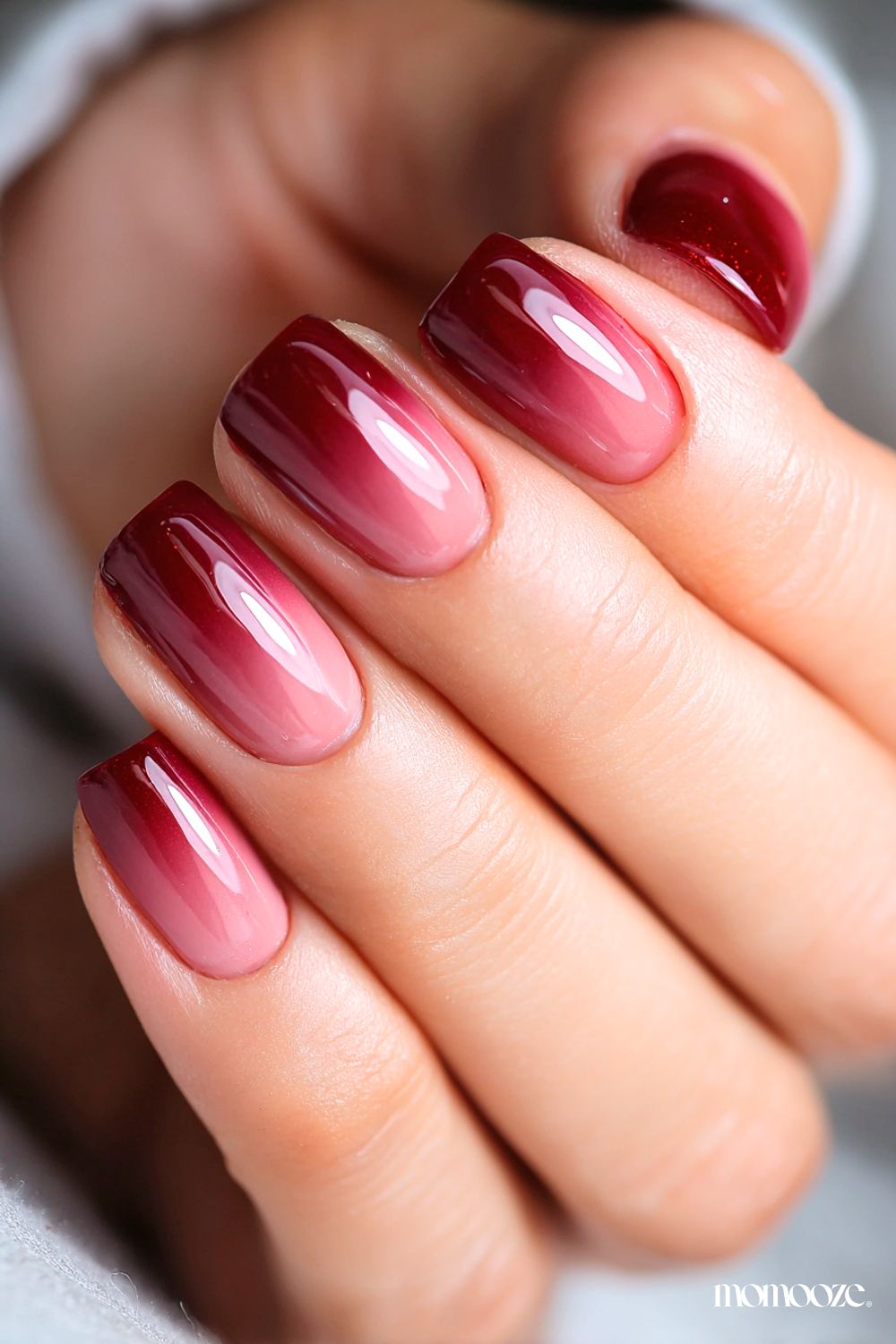 Manucure ombré élégante avec un dégradé d'un rose laiteux vers un rouge framboise intense sur la pointe de l'ongle.